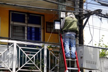 Antipolo Şehri, Filipinler - 16 Mayıs 2020: Bir telekomünikasyon şirketinin çalışanı bir direkte bir dizi kablo üzerinde çalışıyor.