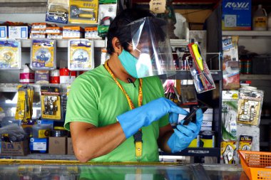Antipolo Şehri, Filipinler - 16 Mayıs 2020: Mağaza sahibi, Covid 19 virüs salgını sırasında işletmelere izin verildiğinde güvenlik önlemi olarak eldiven, yüz maskesi ve yüz maskesi takıyor.