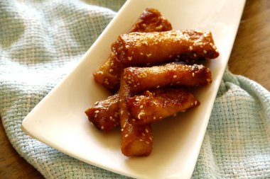 Turon adındaki Filipin yemeklerinin ya da bahar rulosu ambalajında kızartılmış saba muzun esmer şeker ve susam tohumlarıyla fotoğrafı..