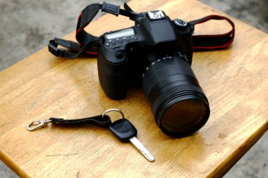Dijital bir SLR veya DSLR kamera ve ahşap bir masada bir araba anahtarı fotoğrafı