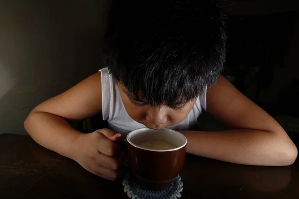 マグカップからホットチョコレートを飲む若いアジアの少年の写真 — ストック写真