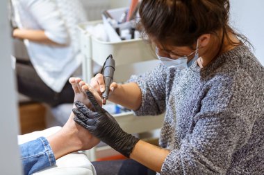 Bir genç manikürcü kız pedikür yapar.