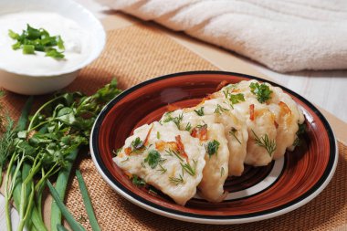 Bir tabak kızarmış soğan ve patates doldurma ile haşlanmış hamur vareniki ile. Ekşi krema ile onu kase.