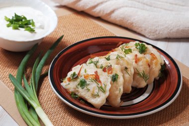 Bir tabak kızarmış soğan ve patates doldurma ile haşlanmış hamur vareniki ile. Ekşi krema ile onu kase.