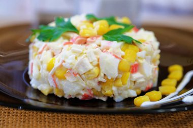 Bir karanlık tabak salataya Yengeç sopa, Mısır, haşlanmış pirinç, yumurta ve mayonez ilavesi ile. Yemek yeşil maydanoz yaprakları ile dekore edilmiştir. Görünümü kapatın.