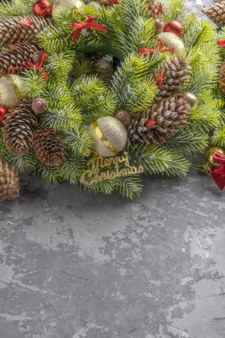 Çam kozalaklı Noel çelengi, toplar, kurdeleler ve palamutlarla dolu beton yüzey üzerinde fotokopi alanı.