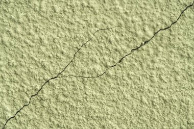 Zeytin boyalı yara bandı çatlaklarla yıpranmış duvarda.