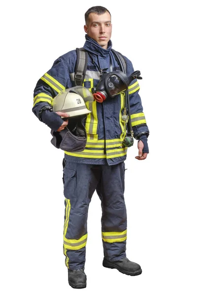 Een jonge dappere brandweerman in een vuurvast uniform staat en kijkt naar de camera met een helm in zijn handen. — Stockfoto