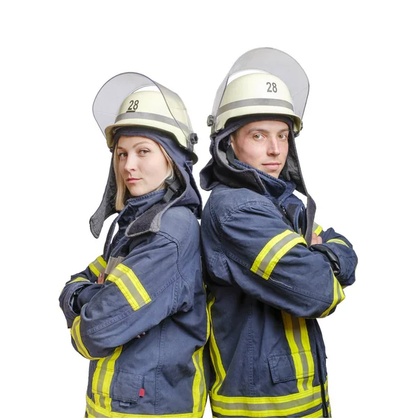 Pareja joven de bomberos con los brazos cruzados de pie espalda a espalda con uniforme y cascos —  Fotos de Stock