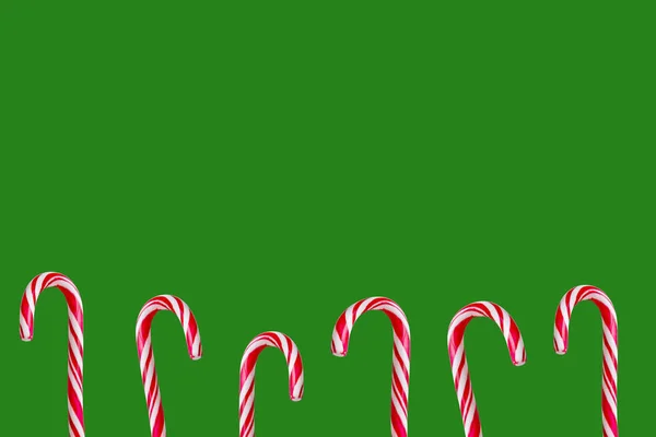 Festive christmas red and white candy canes isolated on green christmas background. — Stock Photo, Image