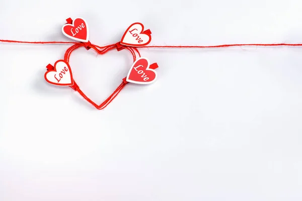Walcowane w kształcie serca czerwona lina z szpilki w kształcie serca na białym tle. — Zdjęcie stockowe