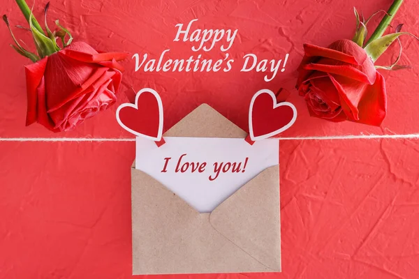 Inscription i love you on card with craft envelope, Happy Valentine Day on red background