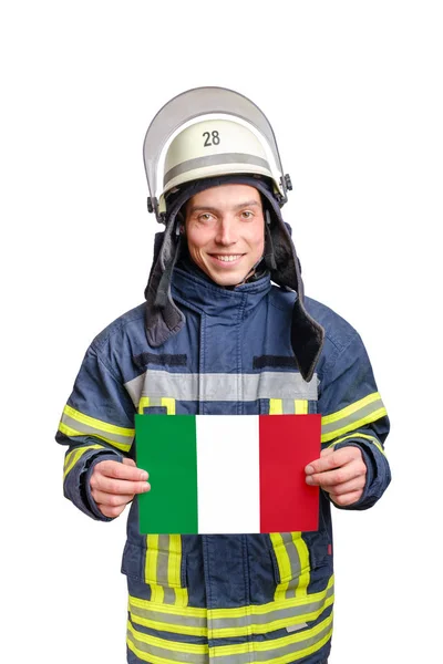Młody uśmiechnięty strażak patrzący w kamerę i trzymający kartkę papieru z włoską flagą — Zdjęcie stockowe