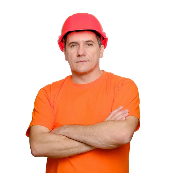 Portret poważnego przystojnego pracownika ze złożonymi ramionami, noszącego kask budowlany i pomarańczowy nieformalny t-shirt — Zdjęcie stockowe