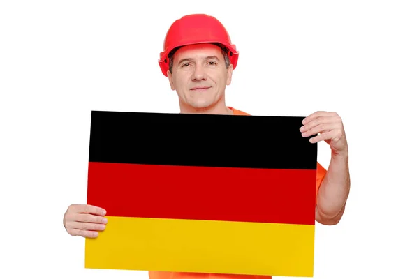 Portret lachende knappe arbeider van middelbare leeftijd met rode harde hoed, met papier met Duitse vlag in handen. — Stockfoto