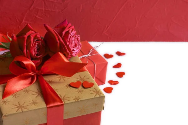 Caja de regalo de oro con cinta roja, rosas y pequeños corazones aislados en blanco, concepto de San Valentín — Foto de Stock