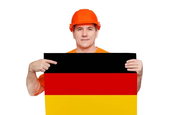Leende medelålders arbetare bär orange hatt, hålla ark med tyska flagga i händerna — Stockfoto
