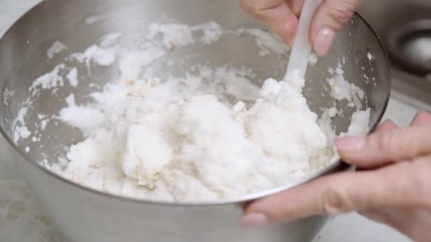 一个女人手里拿着烹饪用的硅胶铲 用面粉 压碎的腰果和砂糖小心搅拌鸡蛋中的白蛋白 然后用金属碗烹调自制的基辅蛋糕 — 图库视频影像