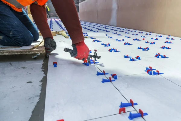 Tiler using plastic clamps and wedges to leveling ceramic tile — 스톡 사진