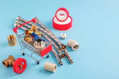 Pirinç top valflı kırmızı alışveriş arabası, polipropilen tesisatı, sepetteki tee. Mühürleme bandı, esnek hortumlar ve mavi arka planda plastik tesisat parçaları. kurulum ve alışveriş kavramı, kopyalama alanı