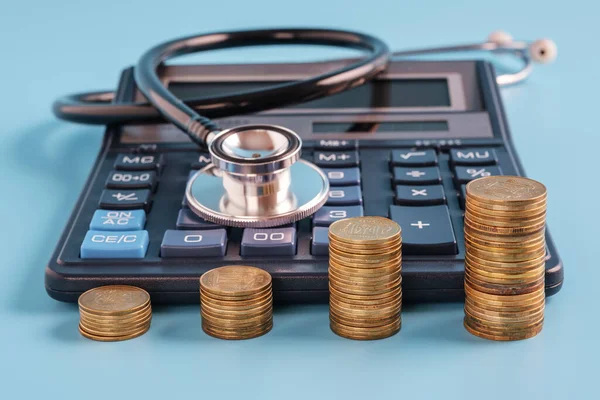 Pilas Monedas Una Fila Ascendente Calculadora Estetoscopio Sobre Fondo Azul —  Fotos de Stock