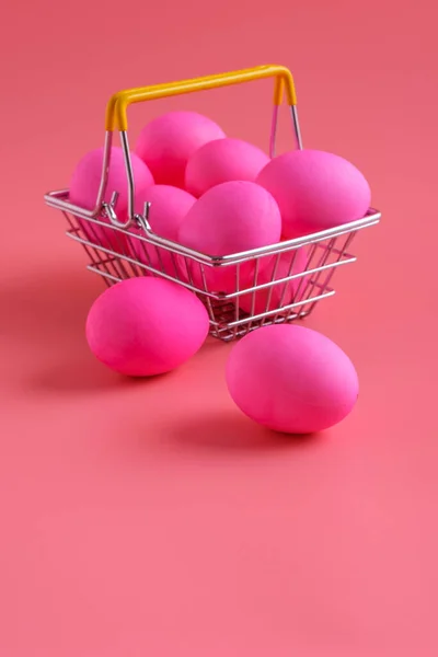 Пасхальные яйца на розовом фоне и повозка . — стоковое фото