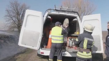 Yahotyn, Kyiv bölgesi, UKRAINE - 20 Mart 2020: itfaiye ekibi, kuru otları söndürmek ve ilkbaharda yanan ormanı söndürmek için itfaiye arabasından hortumu çıkarsın