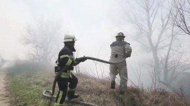 Yahotyn, Kyiv bölgesi, UKRAINE - 20 Mart 2020: itfaiye ekibi kuru otları ve yanan ormanı duman altında söndürdü, yakın plan