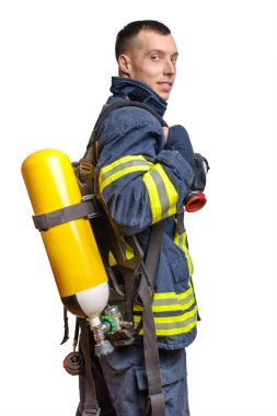 Sırtında Full Facepiece Respirator ve Solunum Hava Silindiri Meclisi ile beyaz arka planda izole edilmiş ateşe dayanıklı üniformayla profilde poz veren beyaz itfaiyeci.
