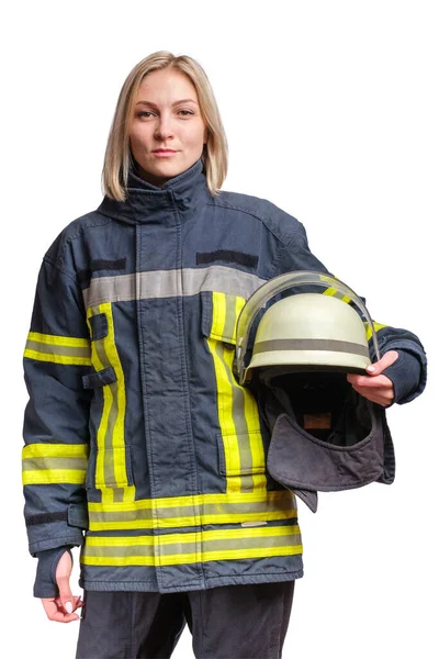 防火の制服を着た若い白人女性の消防士が立っており 彼女の手にヘルメットでカメラを見ています 白に隔離された — ストック写真