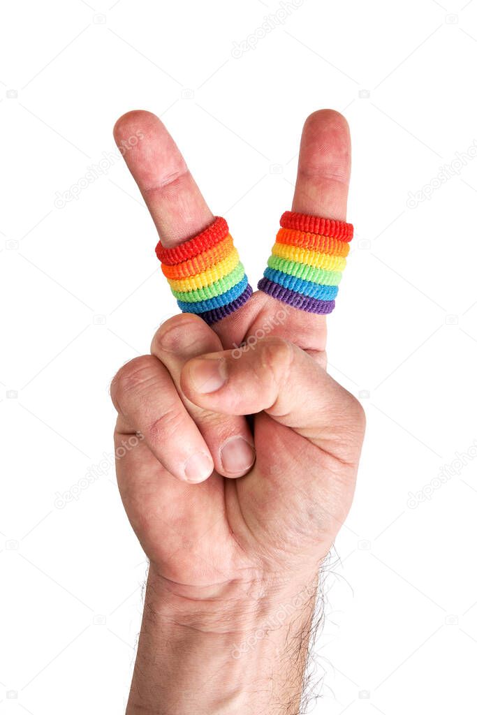 Male hand making the V sign with fingers wears wristbands painted as rainbow flag isolated on white background
