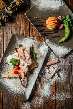 Strudel pasta plaka tarçın, rustik ahşap masa arka plan üzerine pudra şekeri ile