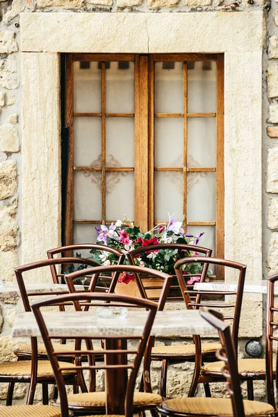 Utcai kávézó, asztalok és székek az ablaknál virágokkal. Olaszország, szabadtéri trattoria — Stock Fotó