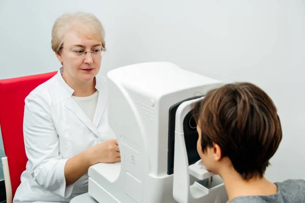 Oogarts vrouw onderzoekt jonge vrouw ogen in kliniek. — Stockfoto