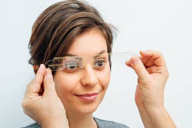 Açık gri arka planda optik deneme çerçevesinde gülümseyen kadın