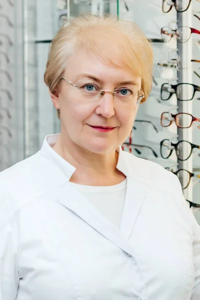 Professionele senior vrouwelijke opticien die een bril aanbiedt in de optische winkel — Stockfoto