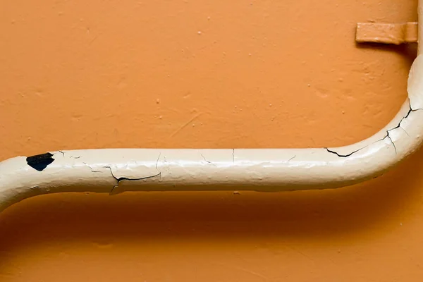 A peeling old pipe against a yellow painted wall Stock Picture