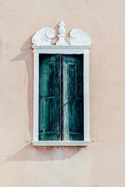 Window with blue-green shutters against light beige wall Stock Photo