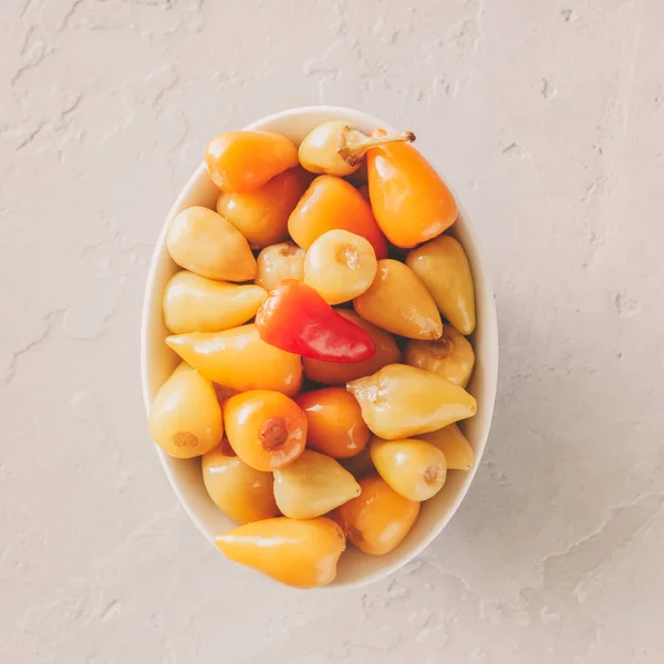 Small pickled hot peppers on a gray concrete background. tinted beige Stock Photo