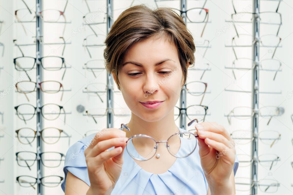 a smiling young female customer squints at the glasses in her hands in the store