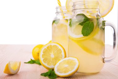 Olgun, sulu ve taze limon, parlak yeşil nane ve maden suyu üzerinde beyaz bir arka plan üzerinde izole ahşap masa lambası, çok renkli ve ferahlatıcı içecekler.