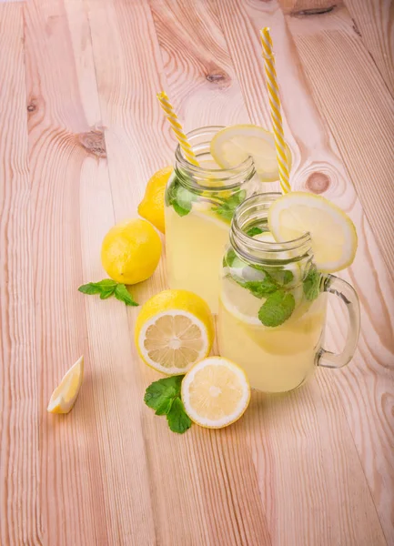 Mojito cocktail ή σόδα ποτά με πράσινο lime και φωτεινά κίτρινα λεμόνια με νόστιμα φύλλα μέντας με κίτρινο καλαμάκια σε φόντο φως τραπέζι. Από την κορυφή άποψη. — Φωτογραφία Αρχείου
