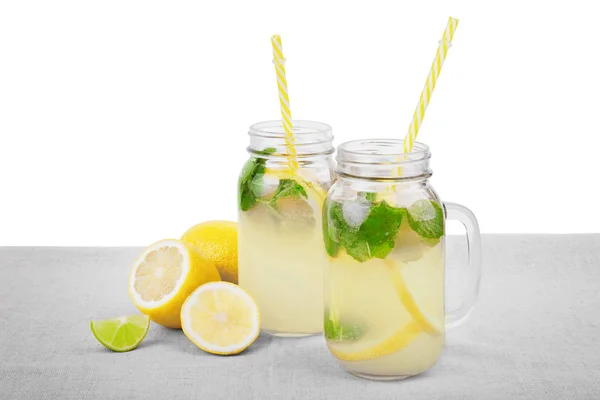 Φρέσκο και τα πολύχρωμα ποτά με ώριμα, ζουμερό και φρέσκο λεμόνια, φωτεινό πράσινο μέντα, νερό για ένα ελαφρύ ύφασμα, απομονώνονται σε λευκό φόντο. Καλοκαιρινά ποτά - κρύα λεμονάδα. — Φωτογραφία Αρχείου