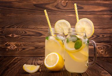 Parlak yeşil nane ve koyu ahşap arka plan üzerinde olgunlaşmış parlak sarı limon soğuk ve lezzetli bir mojito dolu büyük bir mason kavanozlar