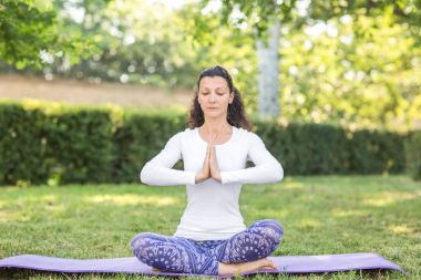 Bir ince kız sportif görünümlü ve spor ve yoga egzersiz yapıyor. Ayak üzerinde oturan ve elleri onun önünde tutan bir kız.