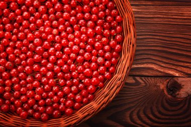 Bir makro ışık sepet kırmızı kuş üzümü ile dolu. Koyu ahşap arka plan üzerinde taze zevkli Frenk üzümü. Parlak kırmızı RIP Frenk üzümü.
