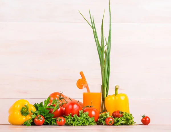 Close-up beautiful vegetables. Salads on a bright background. Glass of juice standing next to the tomatoes, lettuce, pepper.