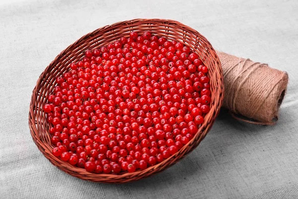 Nahaufnahme roter Beeren in einem braunen Korb auf grauem Hintergrund. reife rohe rote Johannisbeere. geschmackvolle Johannisbeere voller Vitamine. — Stockfoto