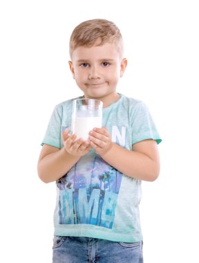 Bir bardak taze süt beyaz bir arka plan üzerinde izole dolu büyüleyici küçük boy gülümseyerek sarı saçlı ve mavi T-shirt tutar.