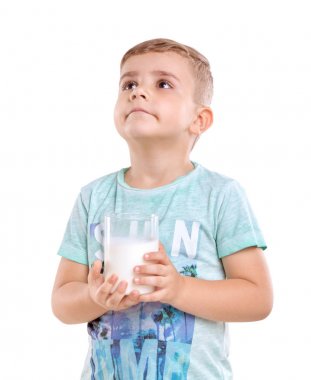 Beyaz saçlı ve mavi tişört mükemmel bir küçük çocuk lezzetli ve sağlıklı süt dolu bir bardak ile ayakta ve, beyaz bir arka plan üzerinde izole görünüyor. Sütlü tatlı küçük bir çocuk.